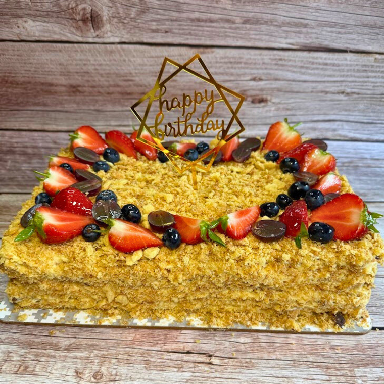 Rectangular Napoleon cake decorated with strawberries, blueberries and a birthday topper