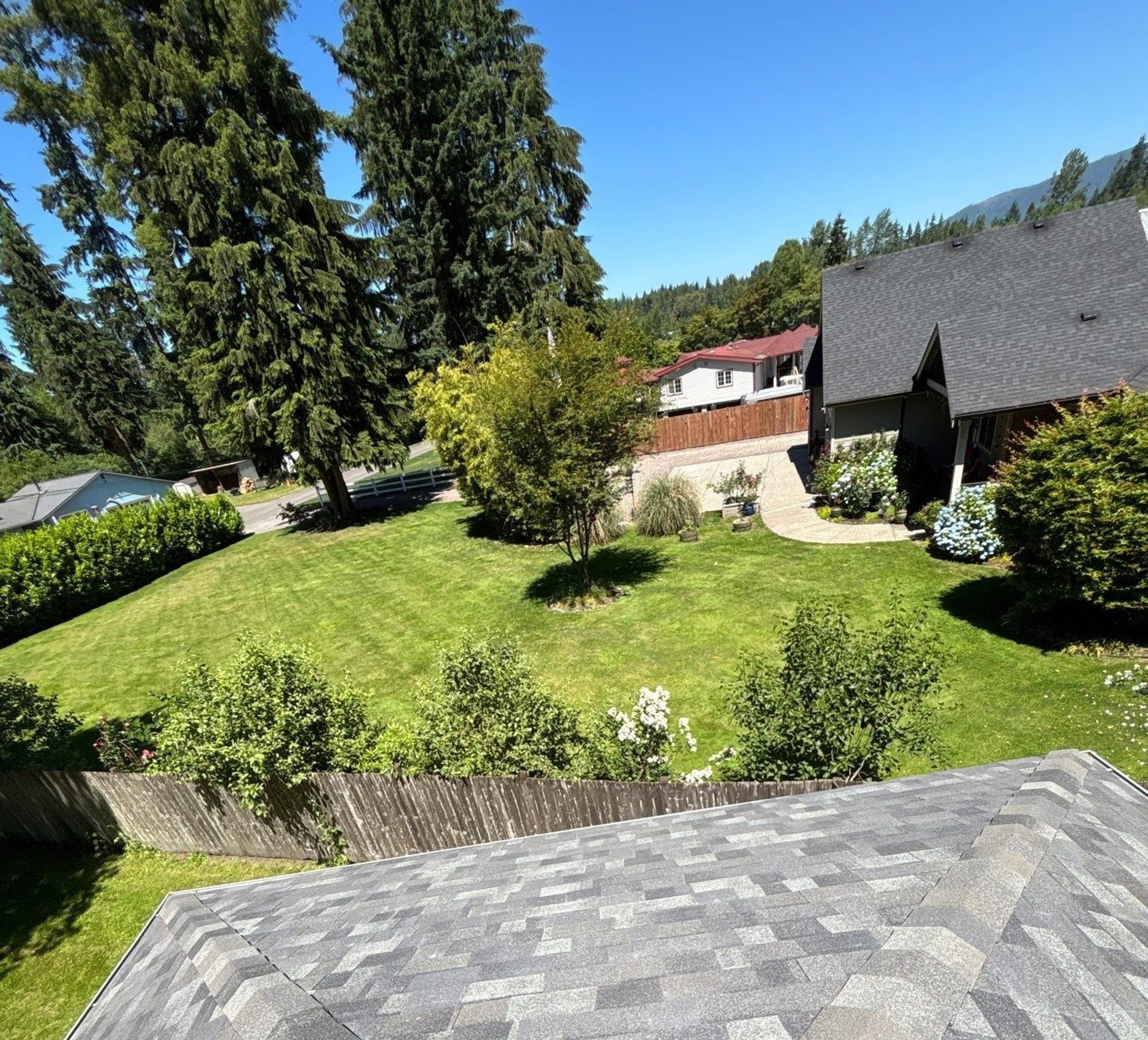 Finished Malarkey Storm Grey asphalt shingle roof with the neighboring homes and tree line beyond, Lake Stevens, WA