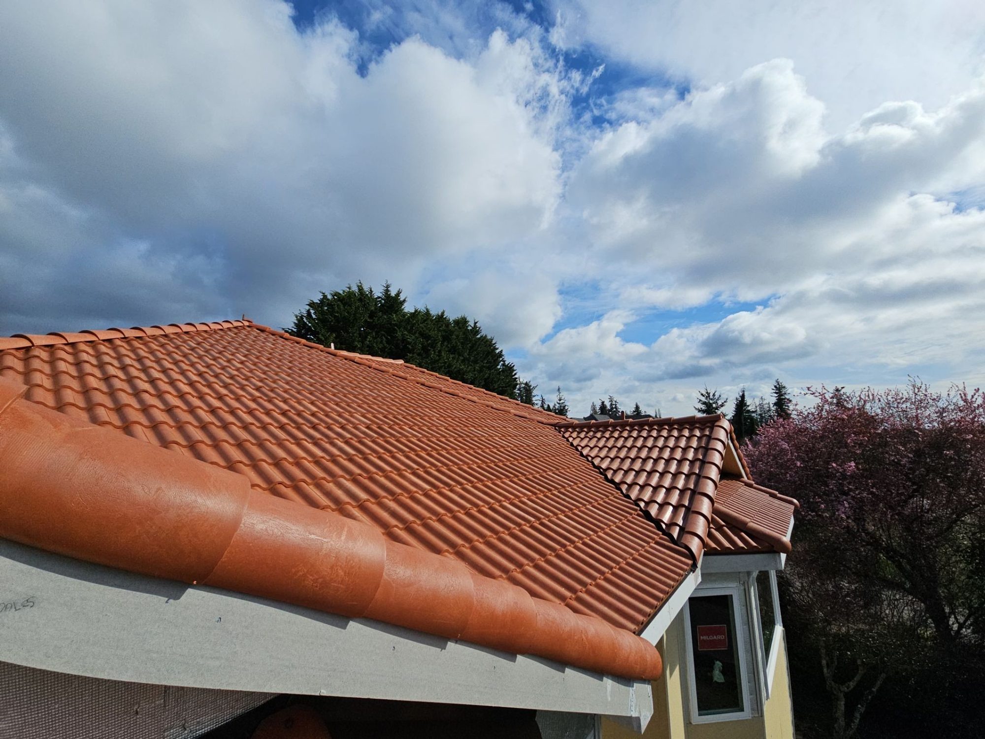 Gable eave of the finished Antique Clay Brava composite Spanish barrel tile roof under blue sky, Mukilteo, WA