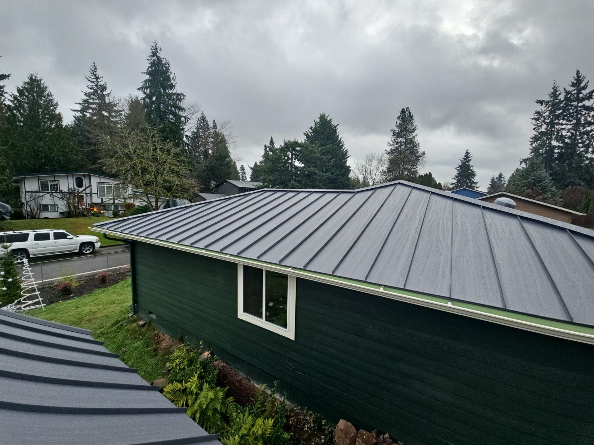 Ground view of the finished Cascade Gray standing seam metal roof on the green Woodinville, WA home