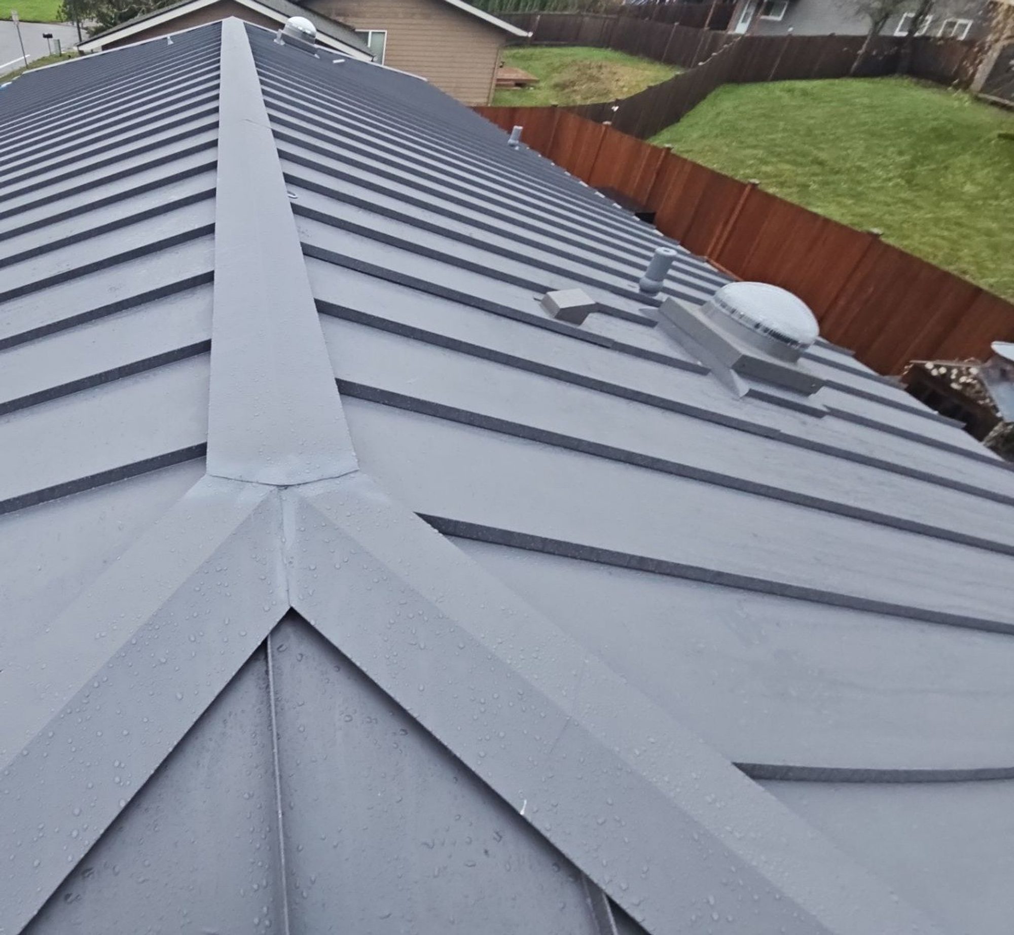 Ridge cap and panel seams of the Cascade Gray standing seam metal roof from the rooftop, Woodinville, WA