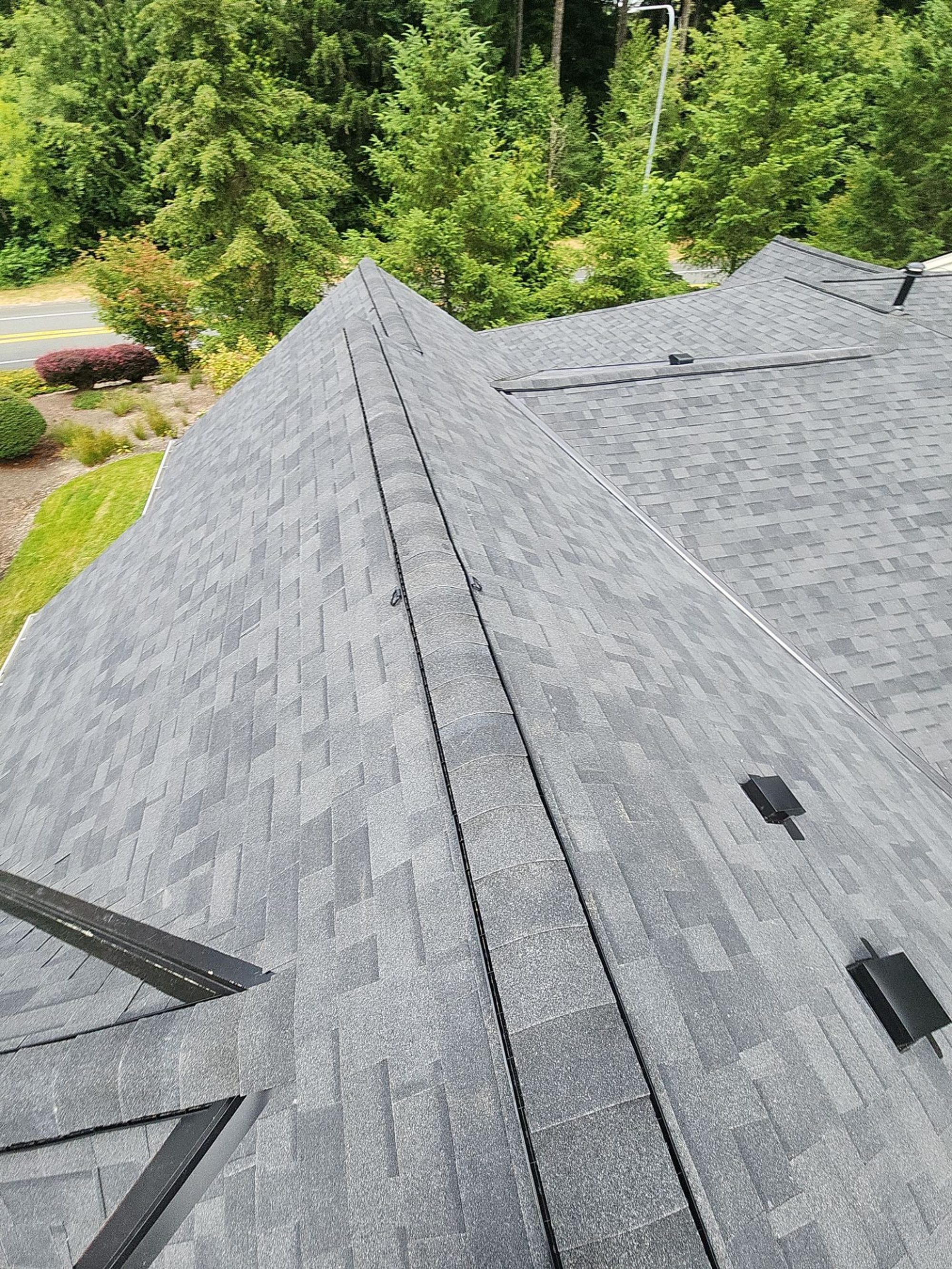 Ridge vent strip on the Malarkey Highlander Midnight Black asphalt shingle roof seen from above, Redmond, WA