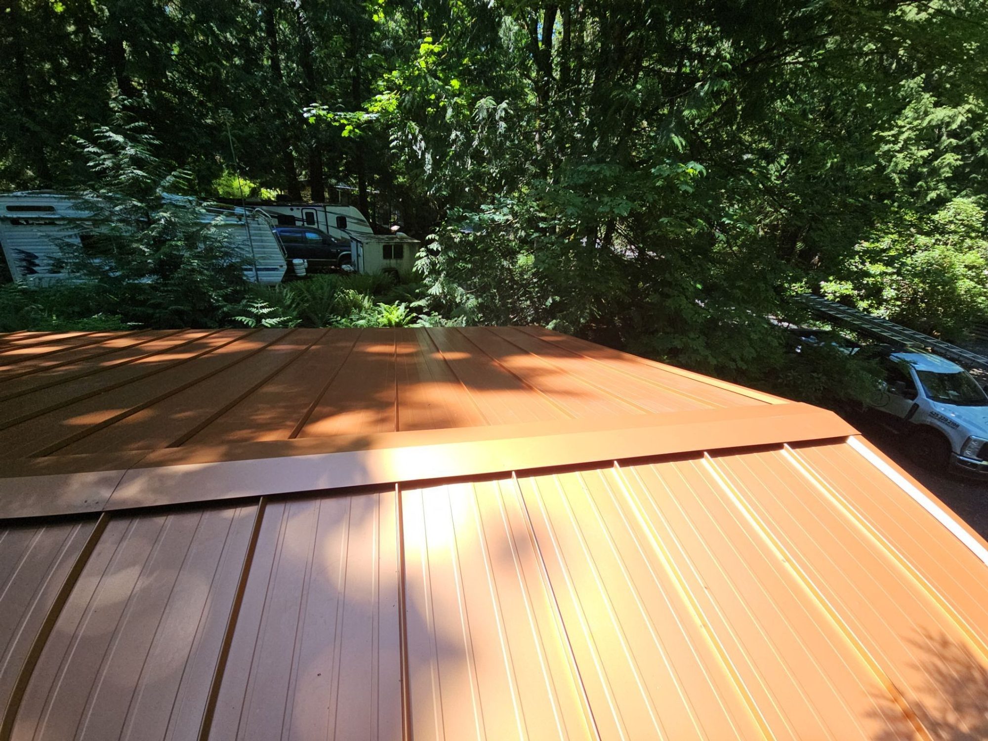 Finished Copper Penny standing seam metal roof above the eave and gutter line, Marysville, WA