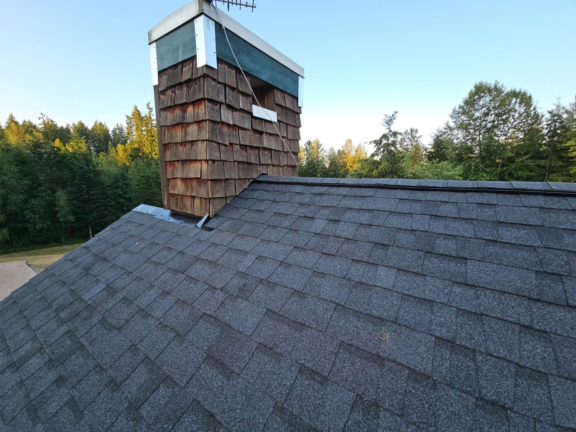 Cedar chimney on Building B's finished Antique Black asphalt shingle roof at evening, Woodinville, WA
