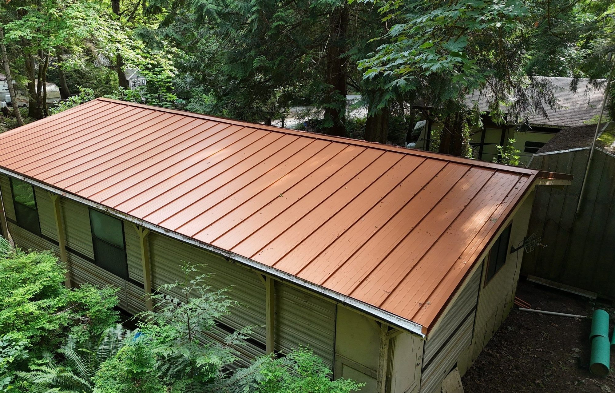 Elevated view of the cabin's finished Copper Penny standing seam metal roof in the trees, Marysville, WA