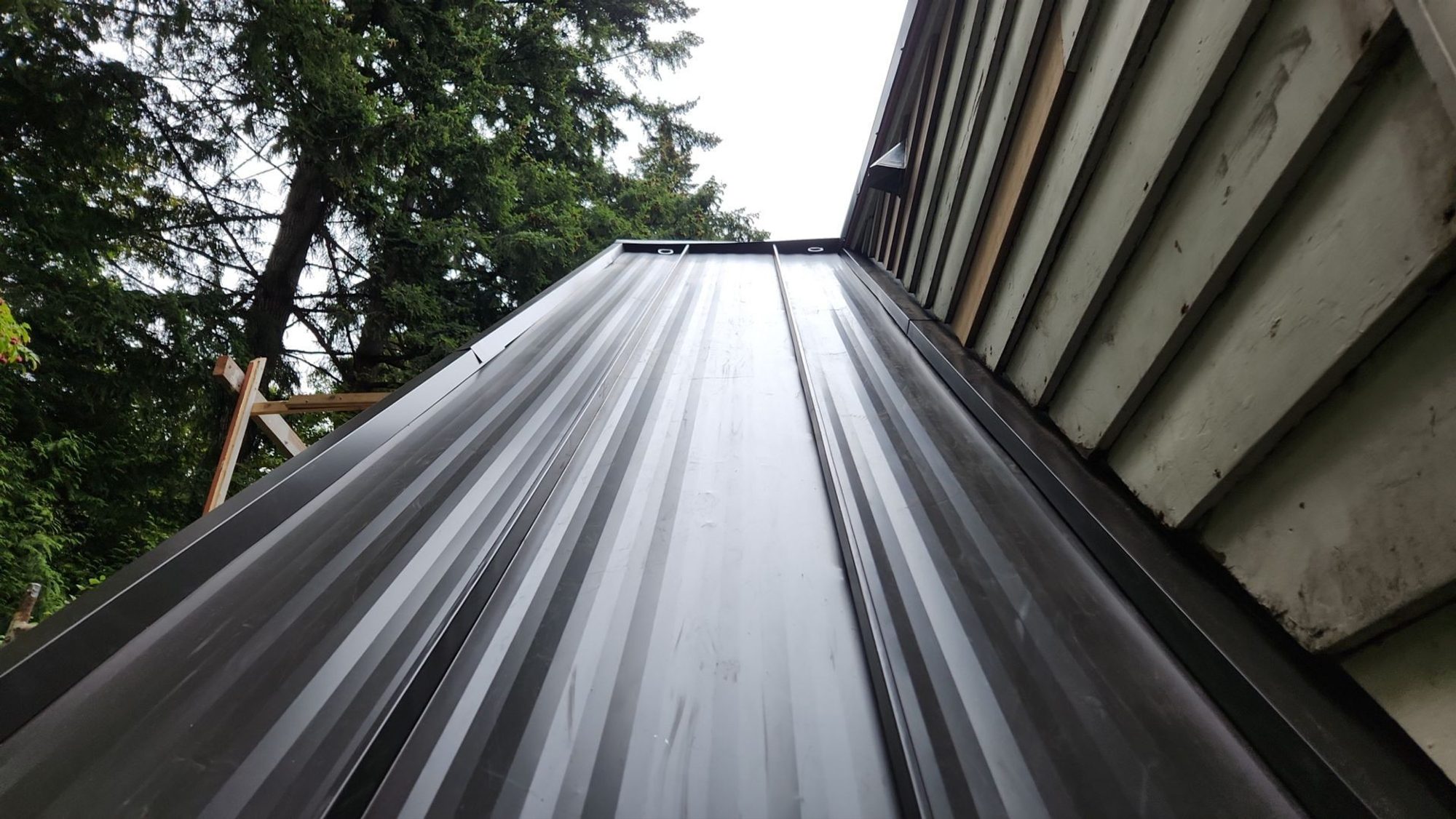 Finished Dark Bronze standing seam metal roof planes with Lake Washington beyond, Bellevue, WA
