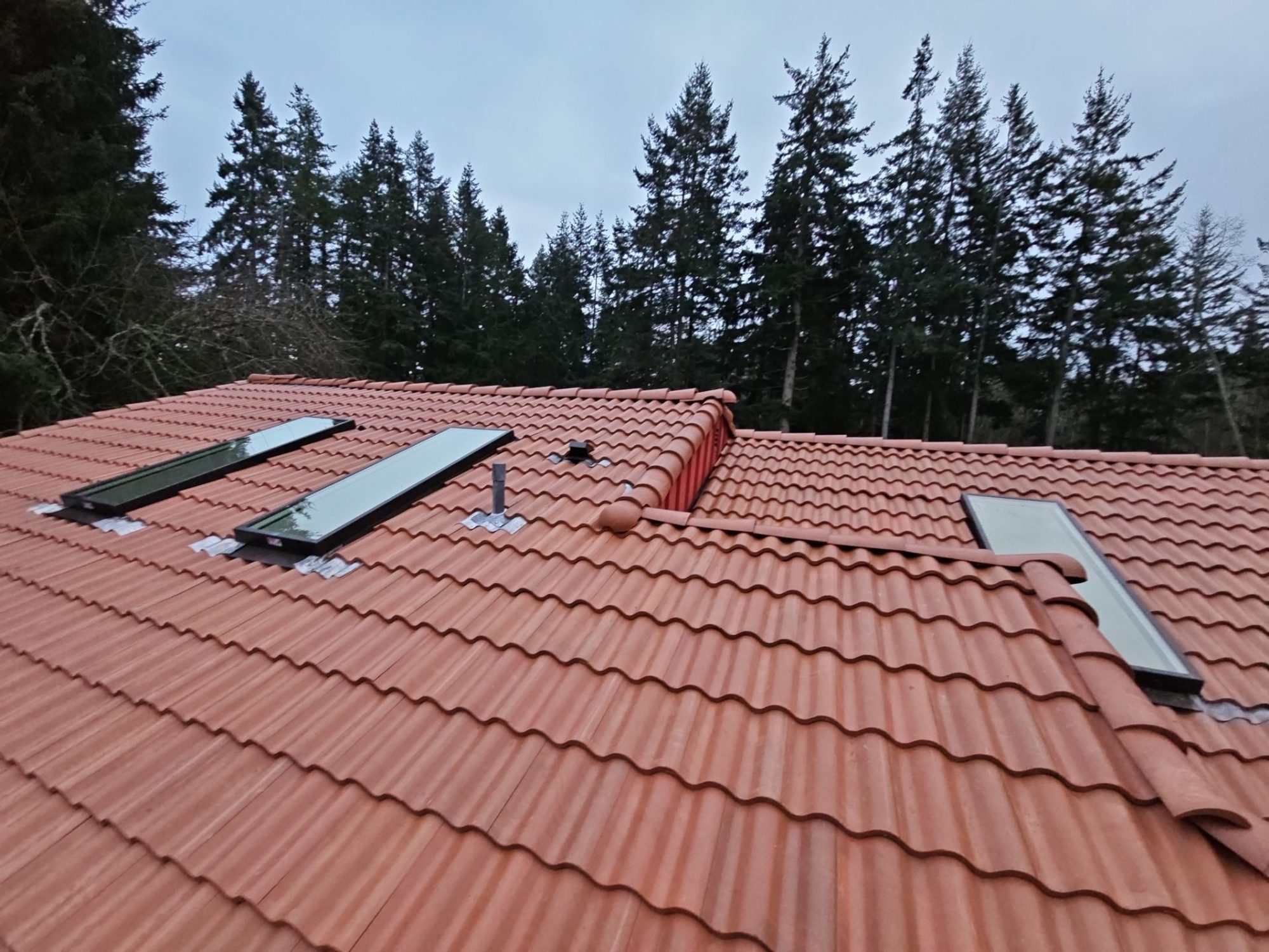 Three skylights along the long slope of the finished Antique Clay Brava composite Spanish barrel tile roof, Camano Island, WA