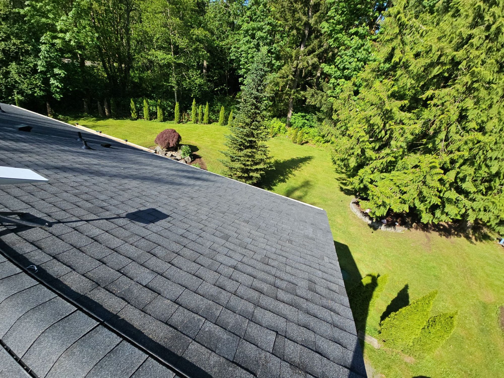 Finished Antique Black asphalt shingle roof with the garden beds and evergreens below, Tulalip Bay, WA