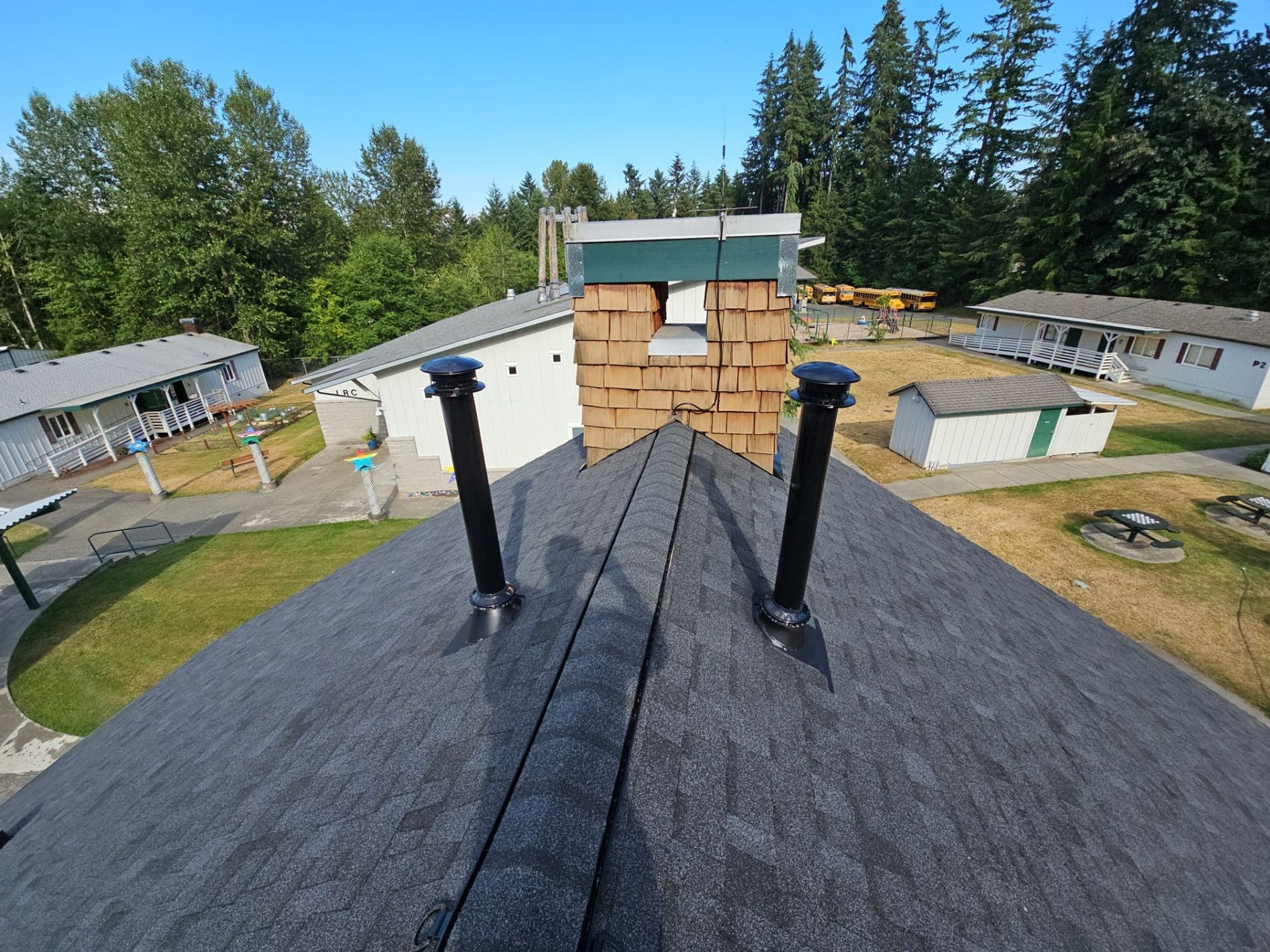 Evening ridge of the Antique Black asphalt shingle roof with pipe vents and chimney, Woodinville, WA