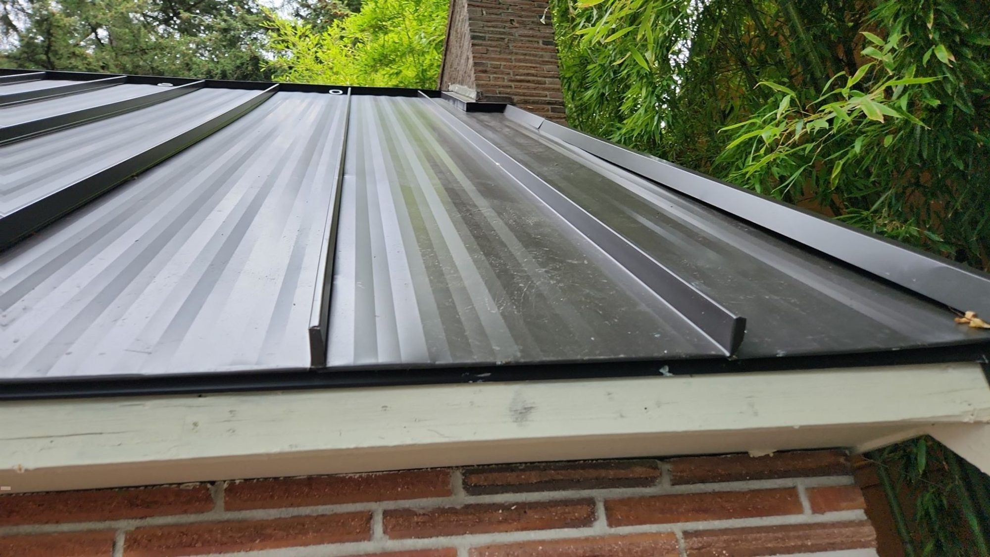Finished Dark Bronze standing seam metal roof meeting the brick chimney, Bellevue, WA