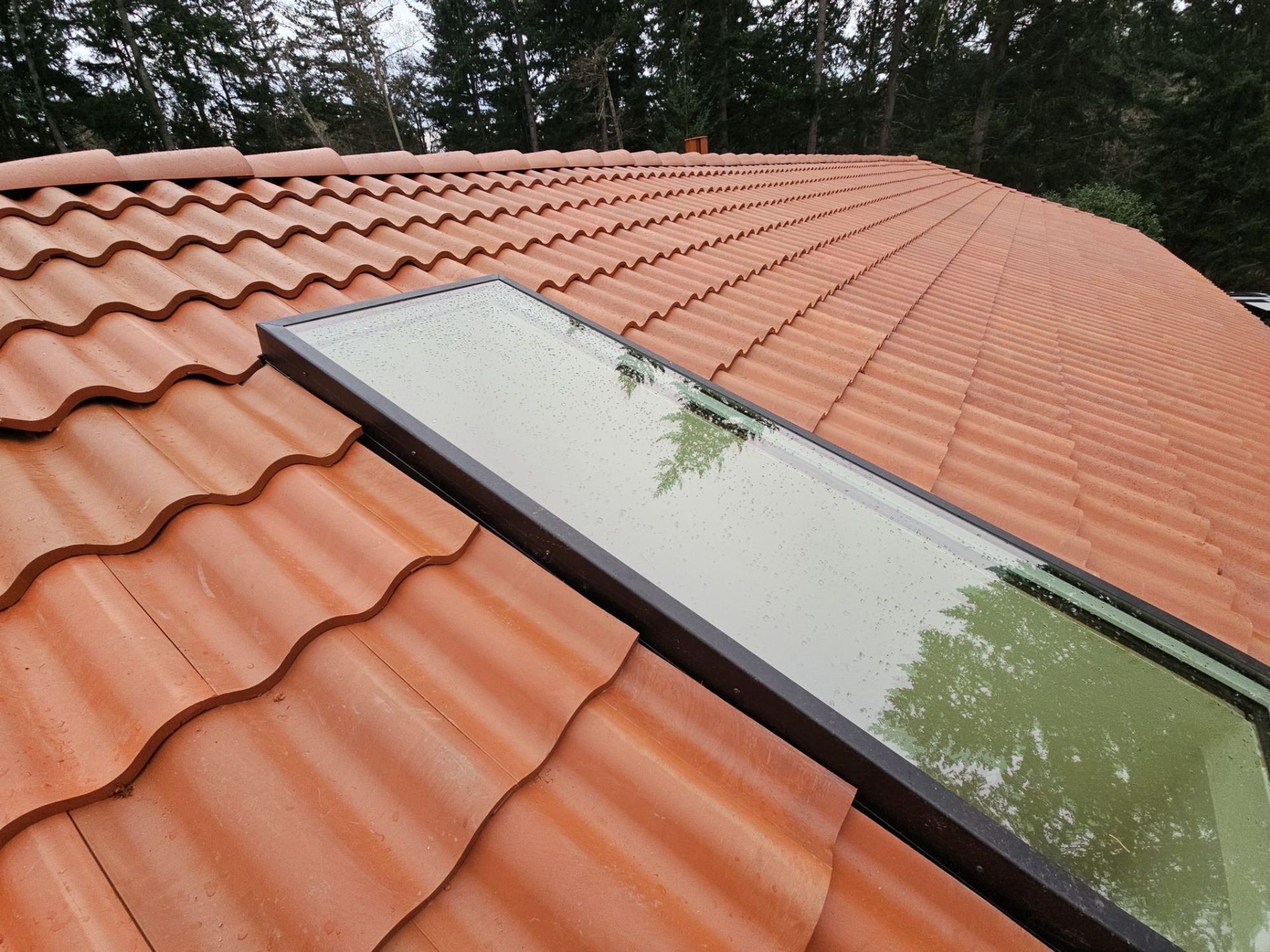 Close-up of a skylight curb and flashing in the finished Antique Clay Brava composite Spanish barrel tile field, Camano Island, WA