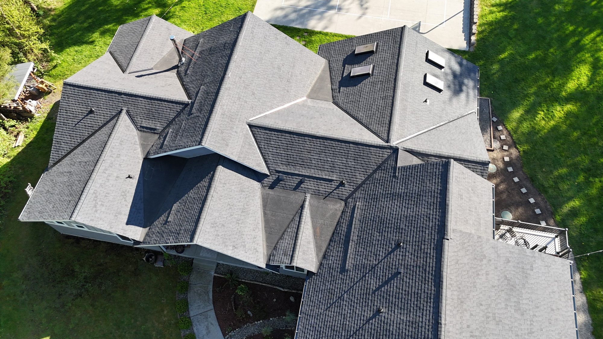 Overhead drone view of the new asphalt roof planes, ridges, and skylights, Lake Stevens, WA