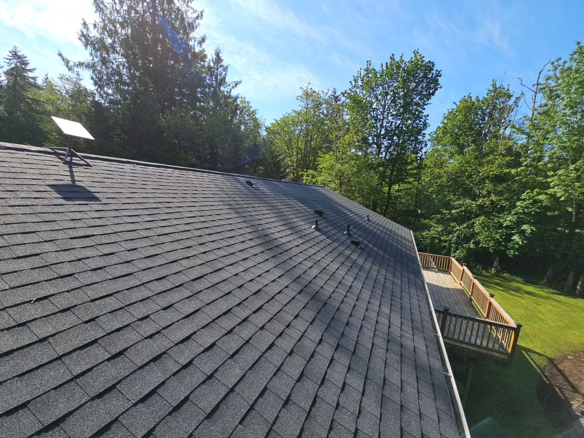 Finished Antique Black asphalt shingle roof plane toward the deck and forest, Tulalip Bay, WA