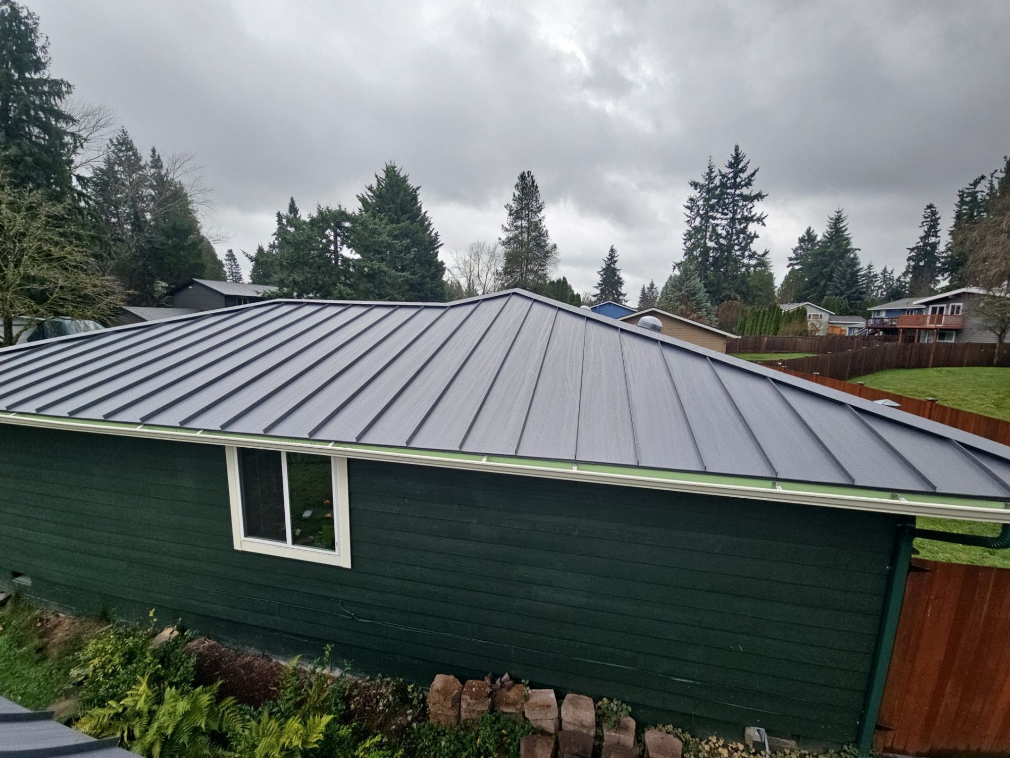 Side elevation of the completed Cascade Gray standing seam metal roof and eave line, Woodinville, WA