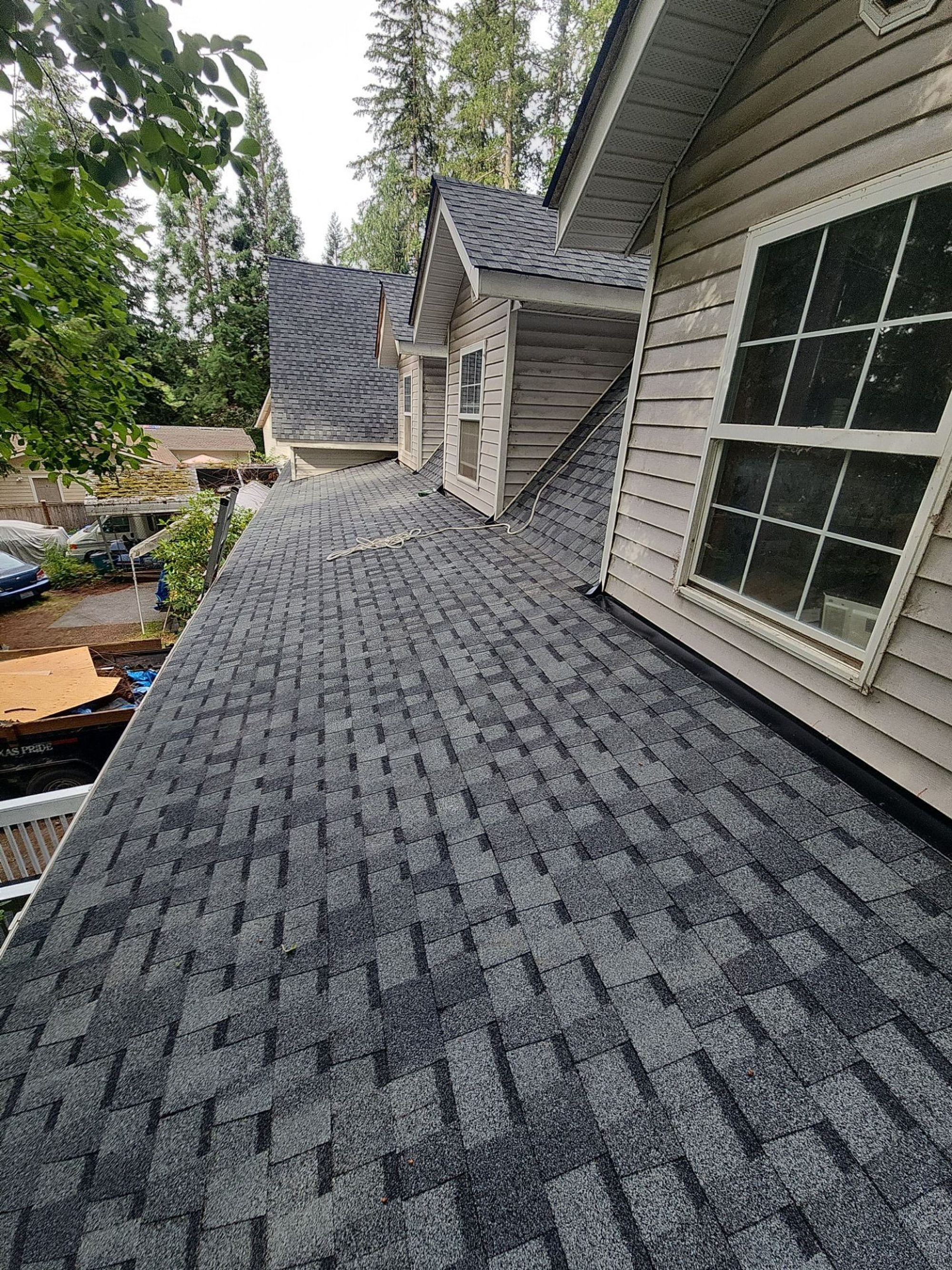 Finished Pabco Premier Pewter Gray asphalt shingle roof along the dormer wall with the forest beyond, Lake Stevens, WA