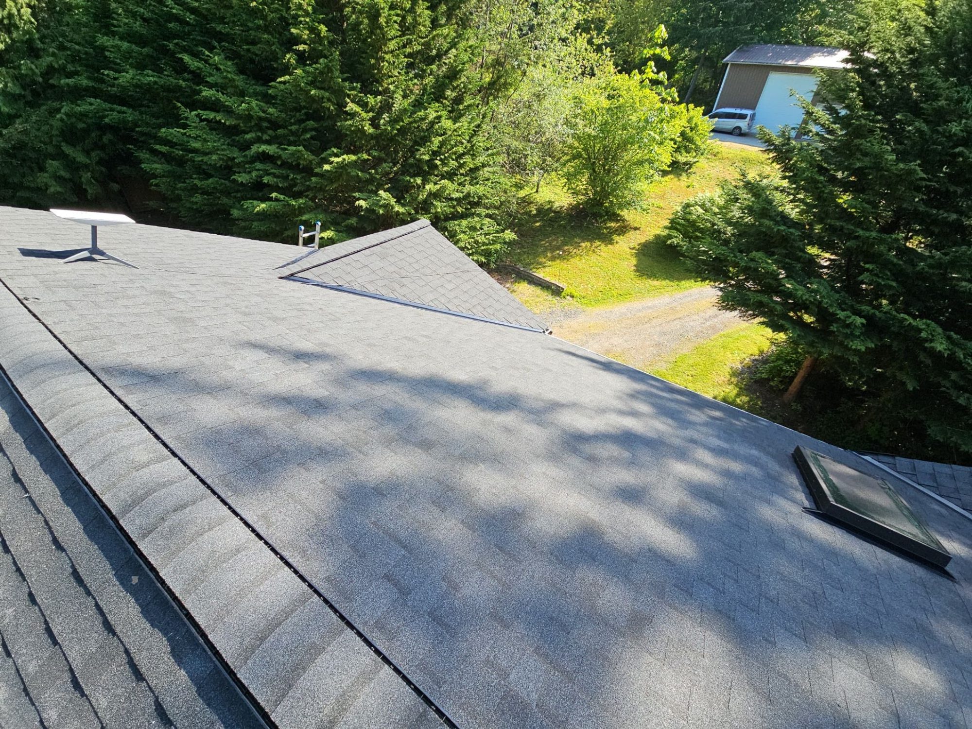 Finished Antique Black asphalt shingle roof planes meeting at the hip above the lawn, Tulalip Bay, WA