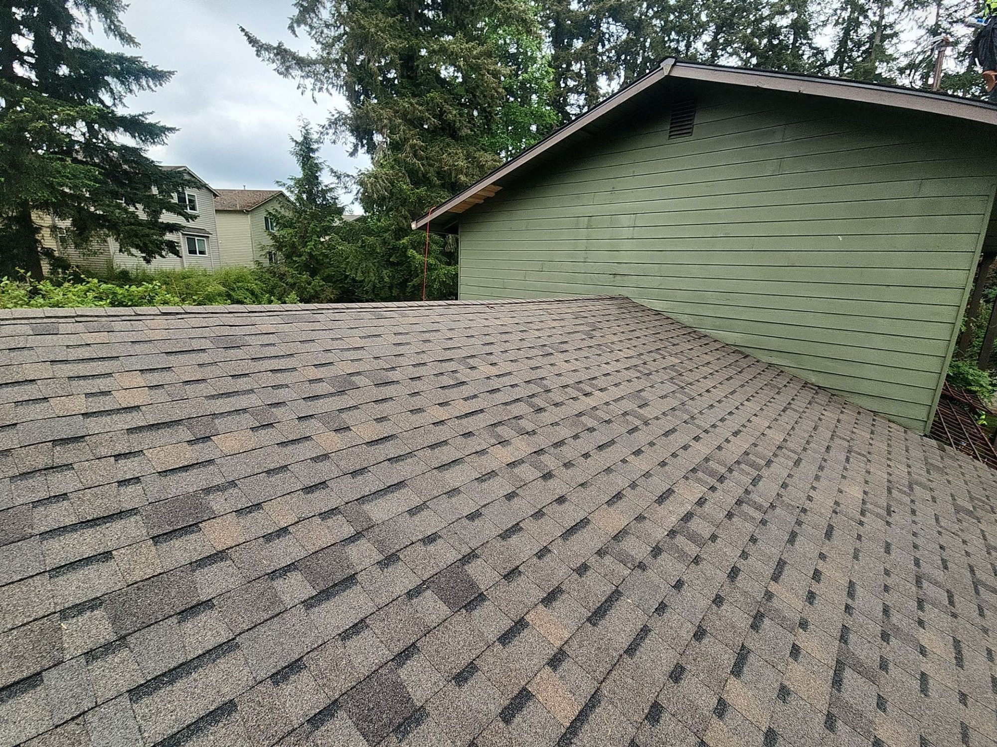 Finished Pabco Oakwood asphalt shingle roof meeting the green gable wall, Lynnwood, WA