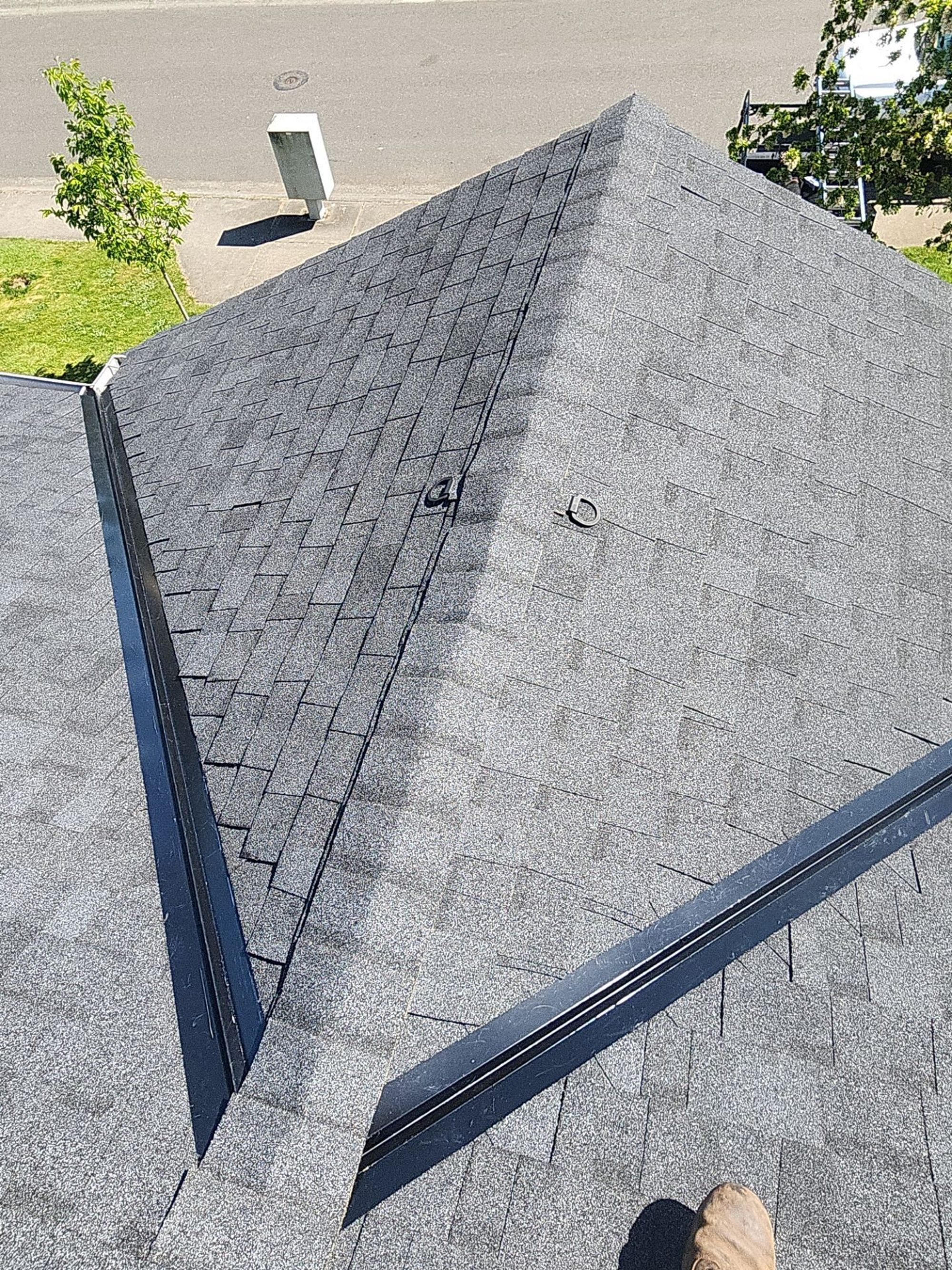 Ridge line of the Pabco Premier Antique Black asphalt shingle roof toward the trees, Bothell, WA