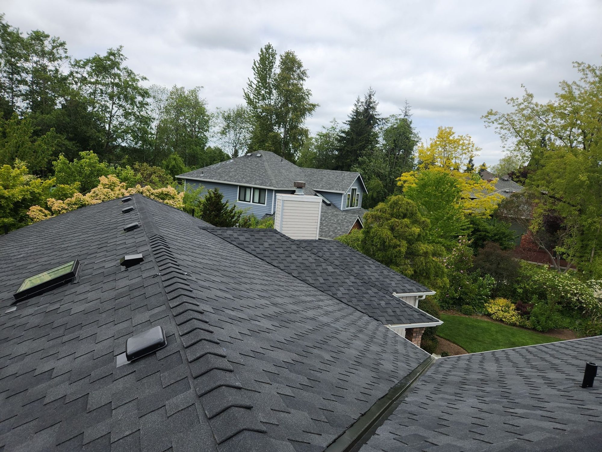 Finished Midnight Black designer shake roof with chimney and skylights, looking across the neighborhood, Brier, WA, by Amor Roofing