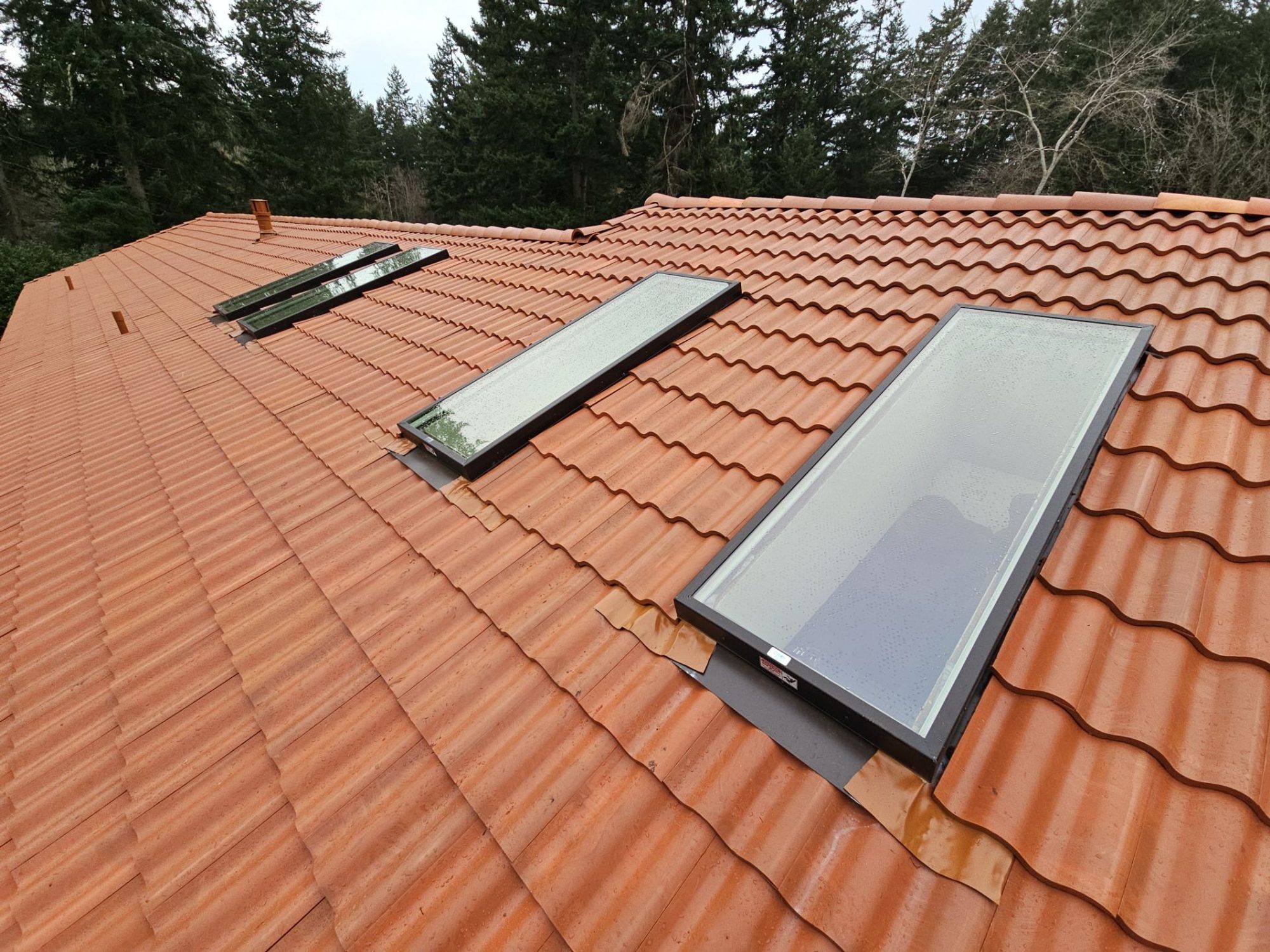 Row of three skylights flashed into Antique Clay Brava composite Spanish barrel tile, Camano Island, WA