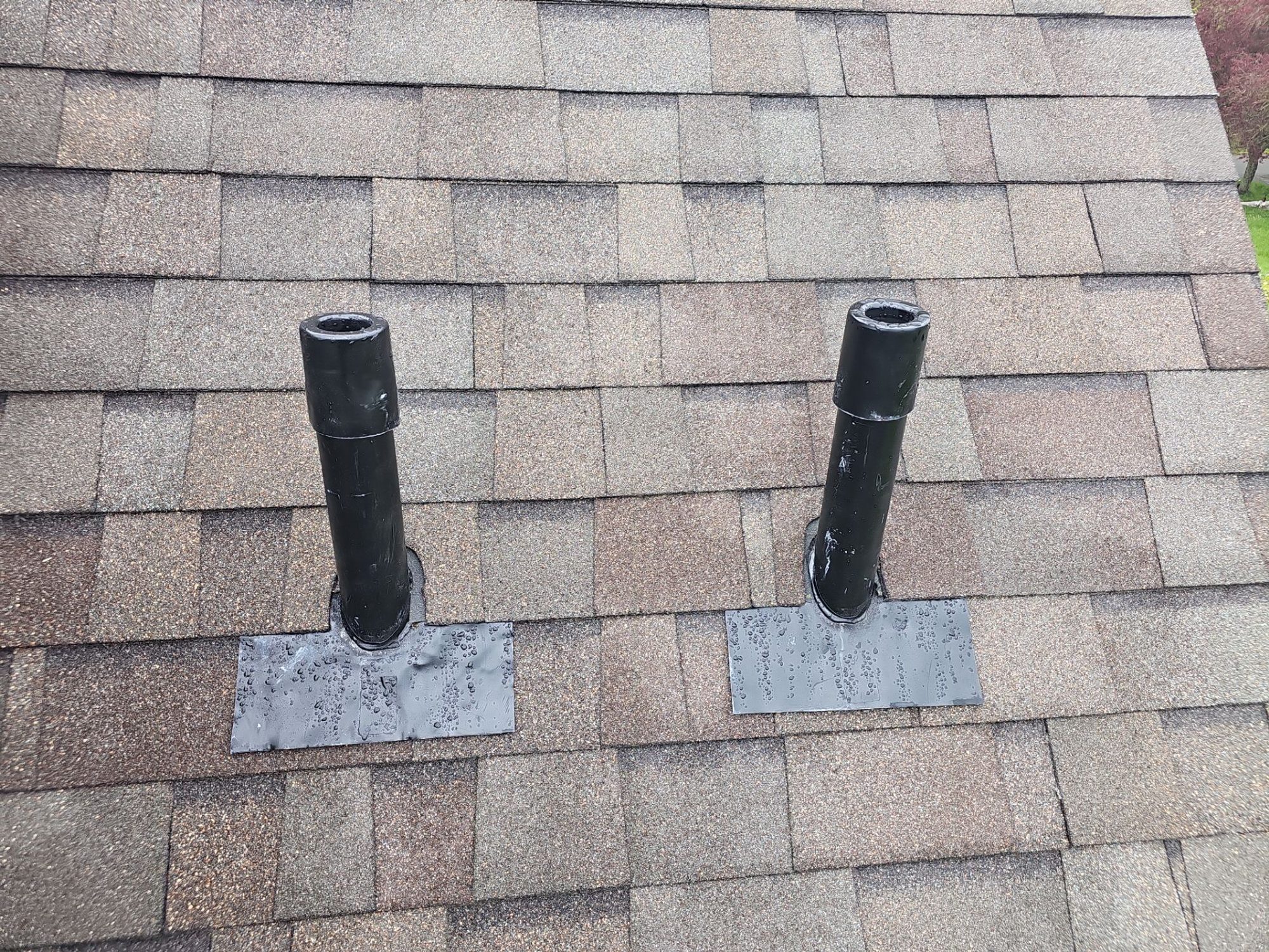 Clean vent-pipe flashing detail on the finished asphalt shingle roof