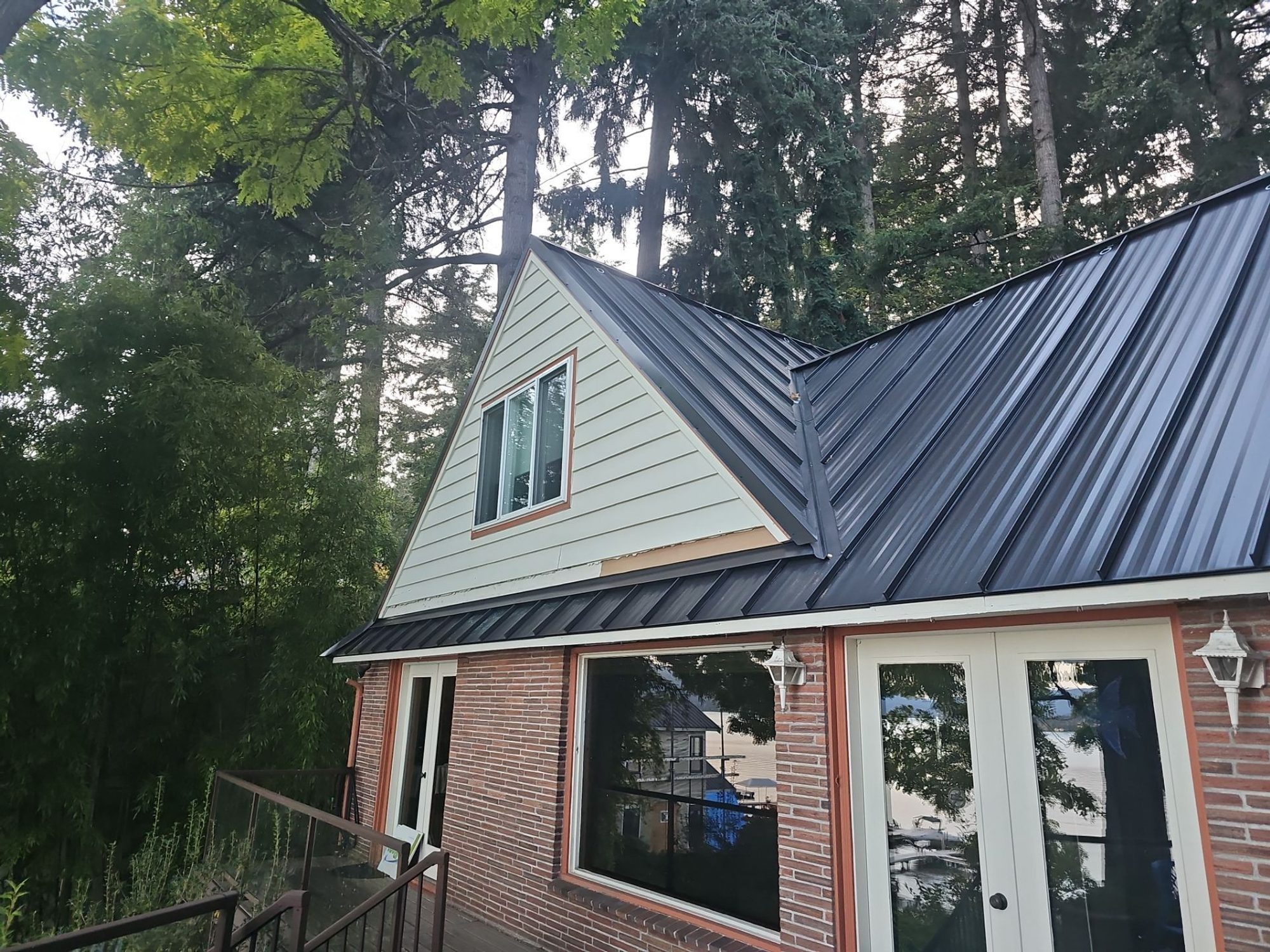 Front of the home with its new Dark Bronze standing seam metal roof under overcast light, Bellevue, WA
