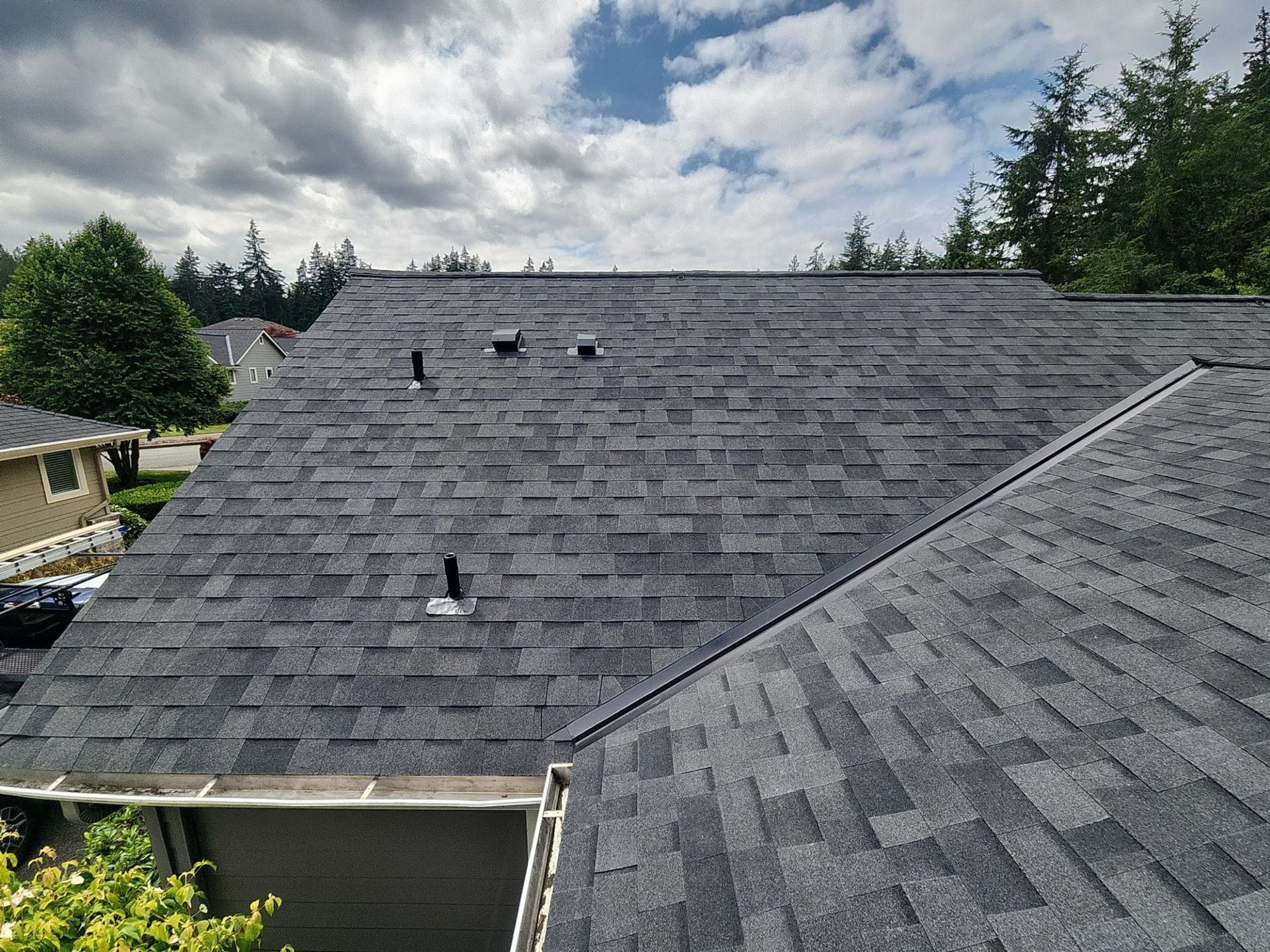 Finished Malarkey Highlander Midnight Black asphalt shingle roof plane with vents under a dramatic sky, Redmond, WA