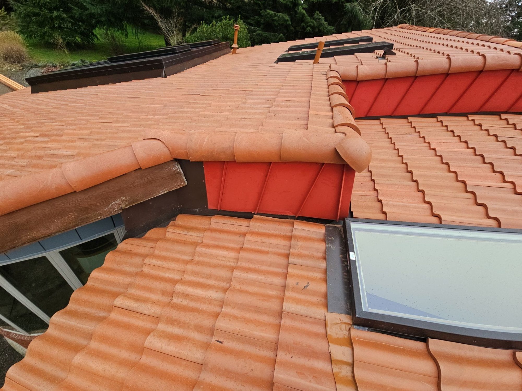 Skylight and wall-flashing detail where two Antique Clay Brava composite Spanish barrel tile roof planes meet, Camano Island, WA