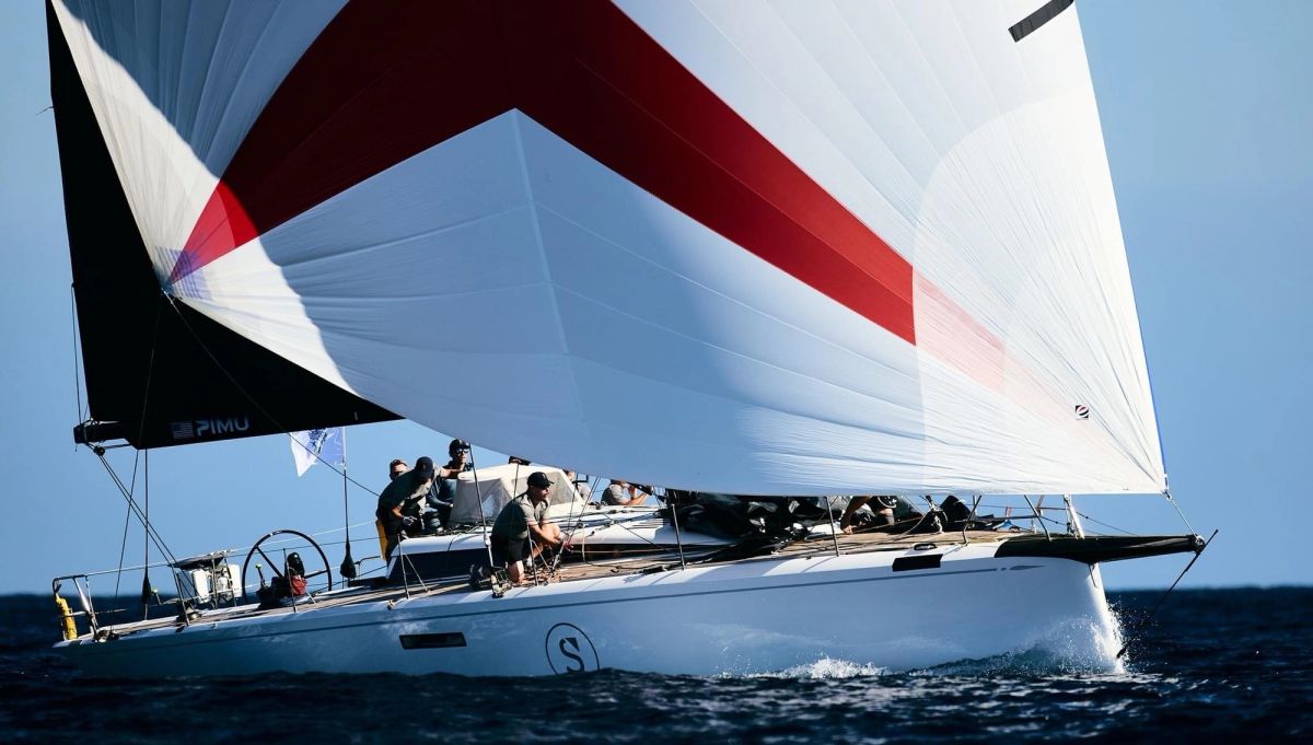 Red and white spinnaker close-up with crew working the deck