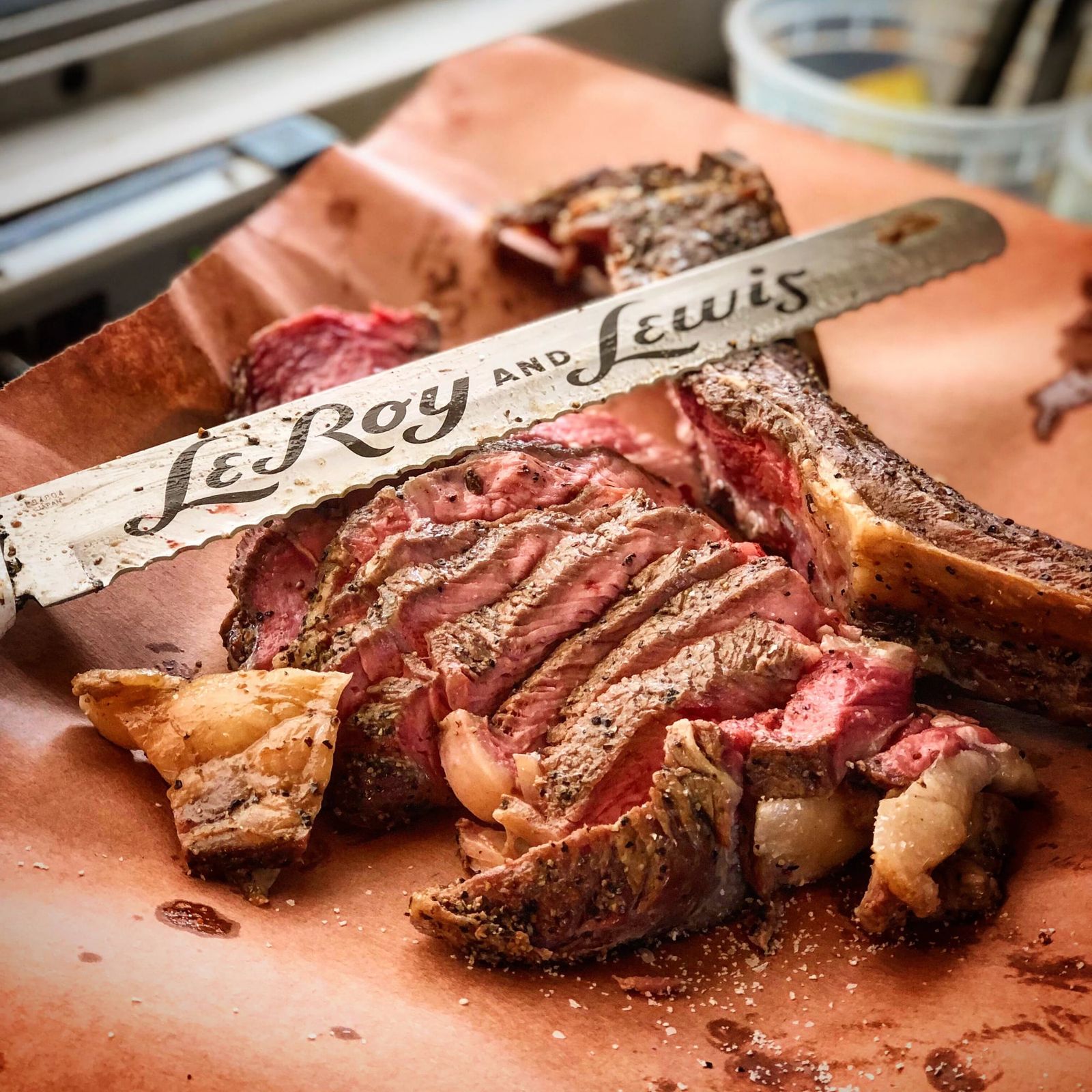Sliced bone-in steak on butcher paper under a LeRoy and Lewis carving knife