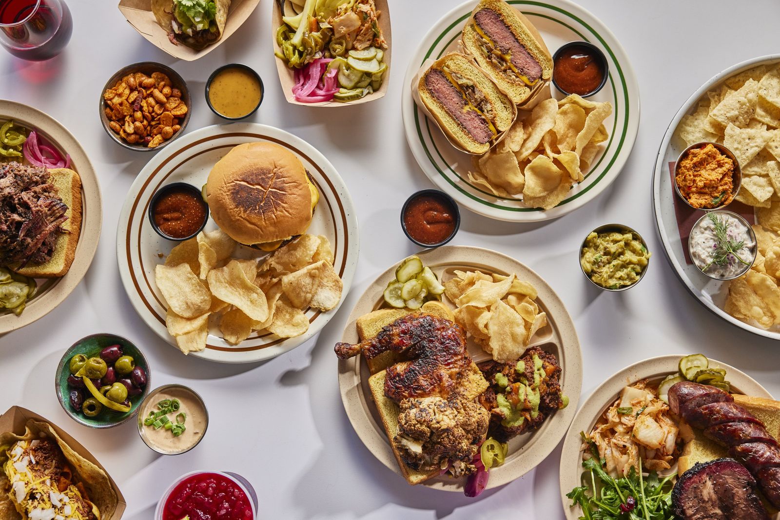 Plates across a table: the L&L burger, smoked chicken, cauliflower, sausage, brisket sandwich and sides