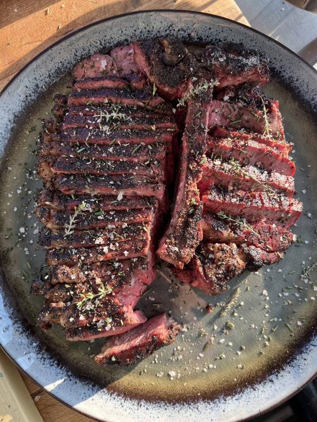 A bone-in steak, sliced and finished with thyme, rosemary and flaked salt