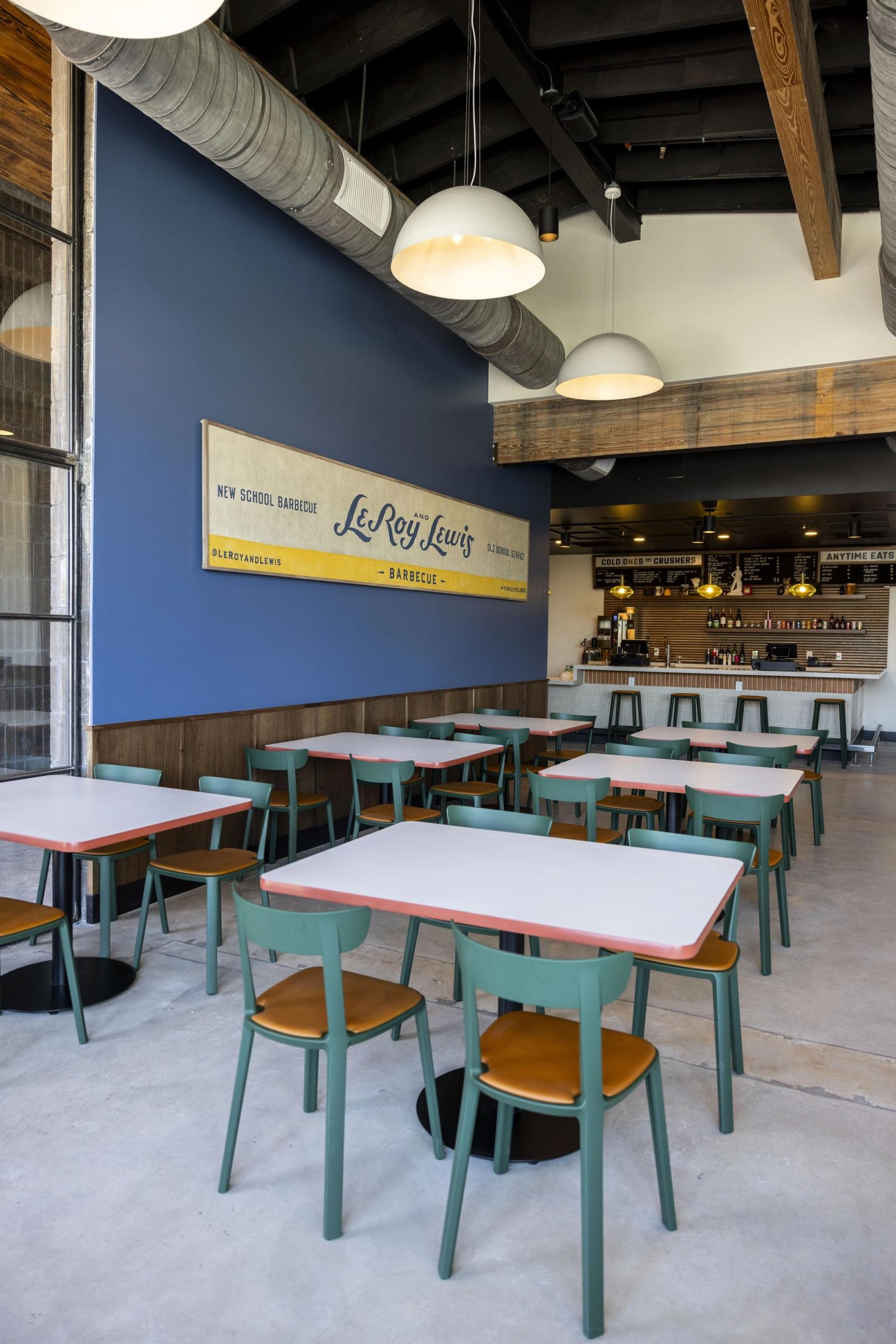 The LeRoy and Lewis dining room: their banner sign on a blue wall, tables, and the bar behind