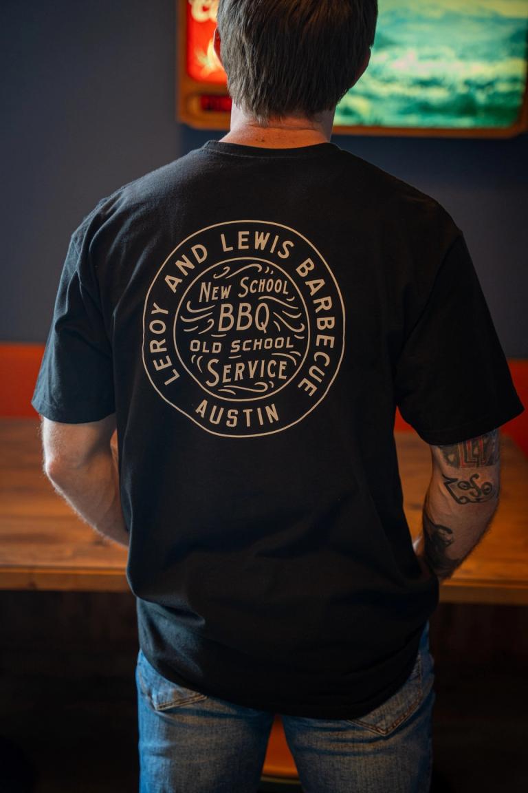 The back of the black shirt: the round LeRoy and Lewis seal, New School BBQ, Old School Service, Austin