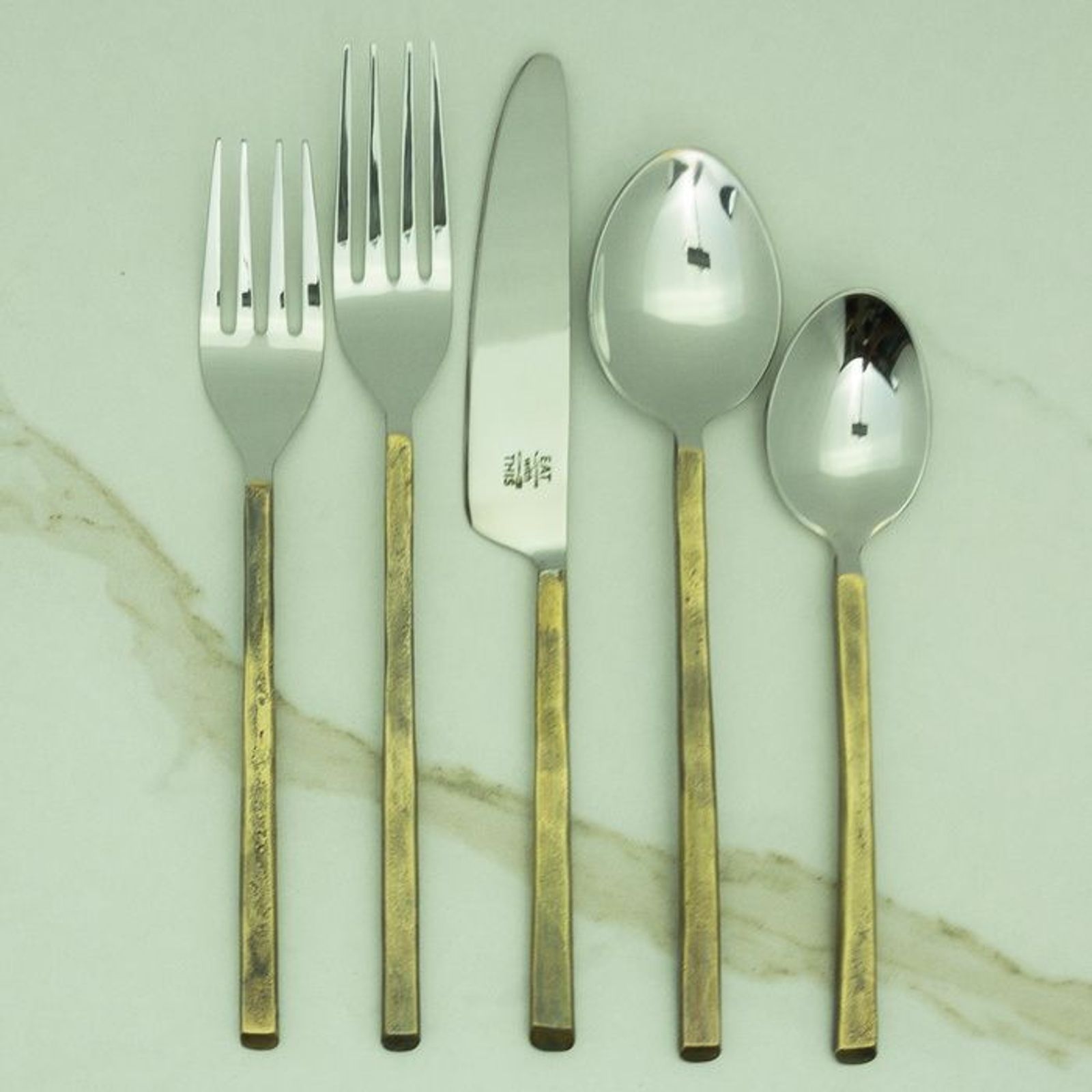 Brass flatware flatlay on a sage place setting