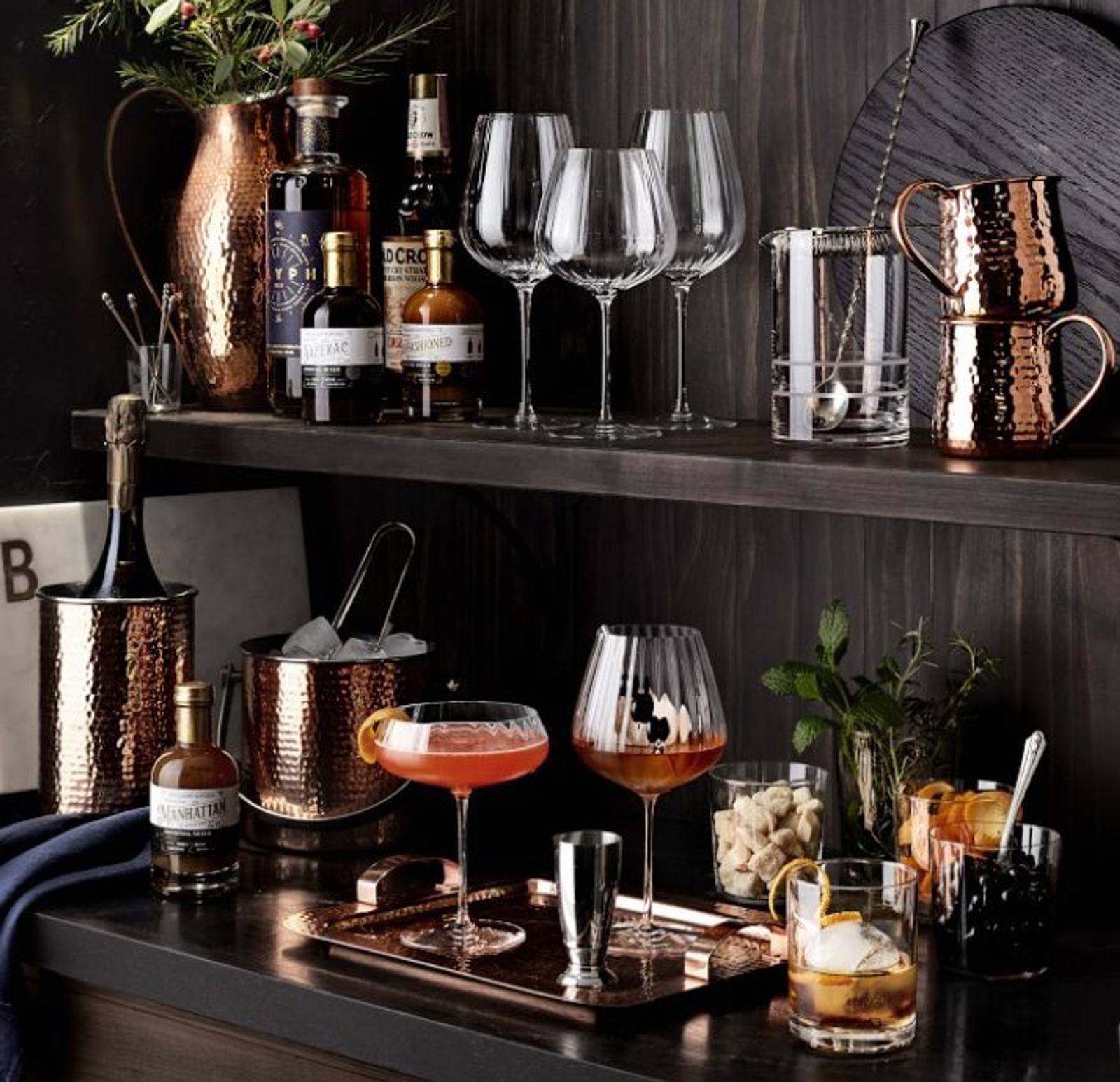 Hammered copper barware styled on a dark bar cart