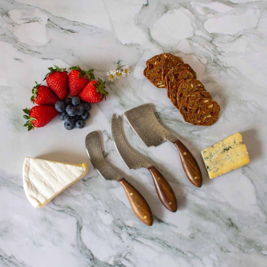 Cheese knives on a marble board with berries