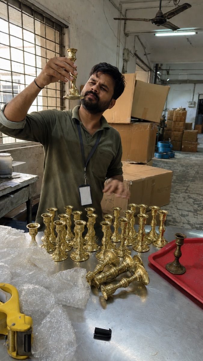 Quality inspector checking cast-brass candle holders before packing
