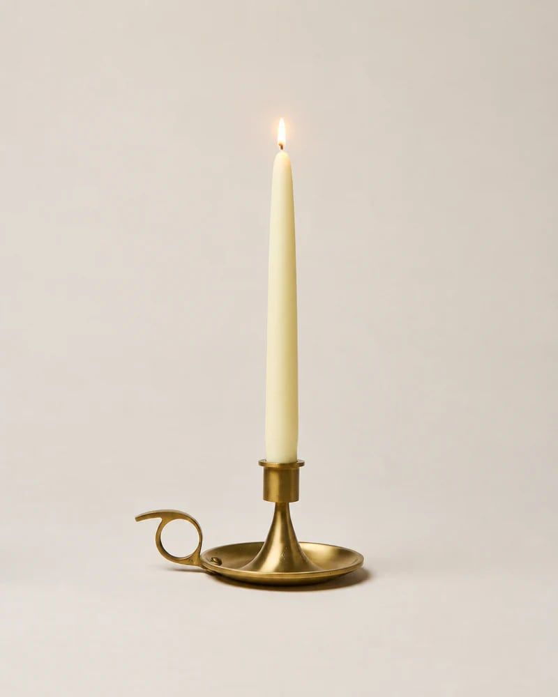 Brass chamberstick with a lit taper candle