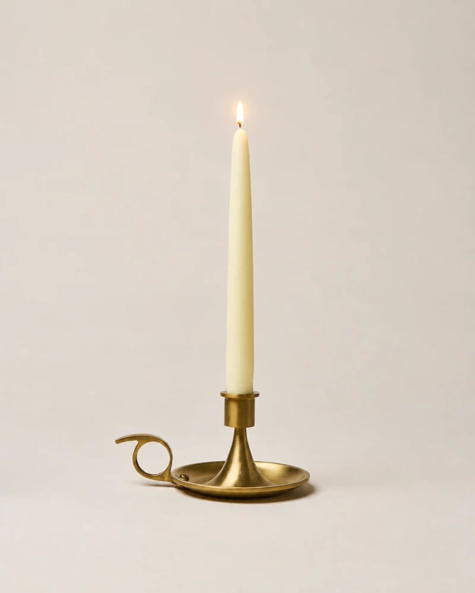 Brass chamberstick with a lit taper candle