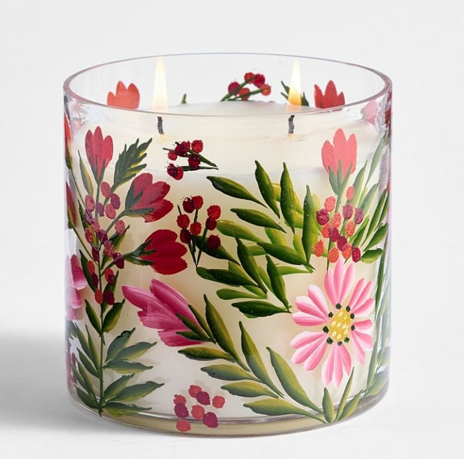 Lit candle in a glass vessel with pressed pink and red botanicals