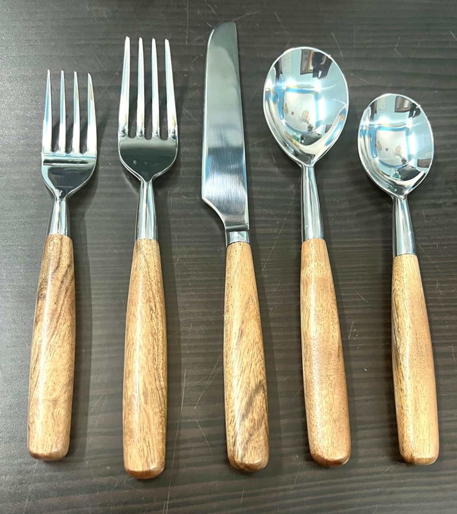 Wood-handle stainless flatware on a dark plate
