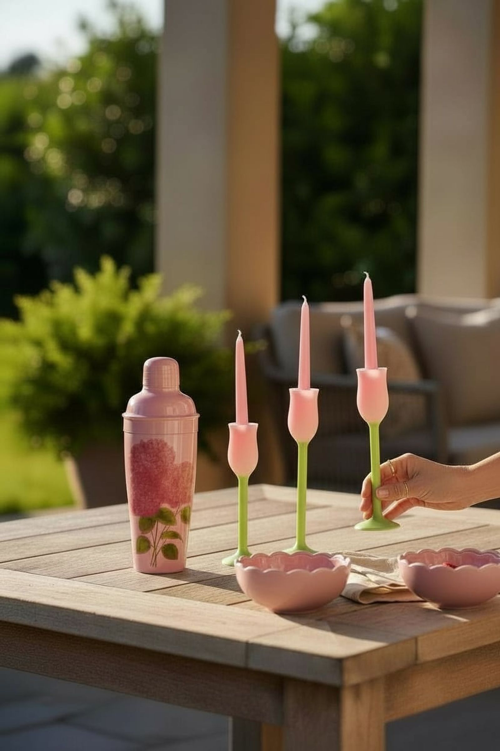 Outdoor table set with a cocktail shaker, taper candles and ceramic bowls