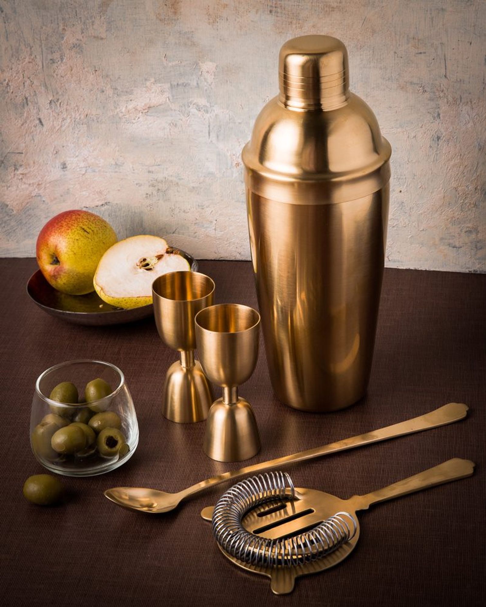 Brass cocktail shaker, jiggers and strainer styled on a bar