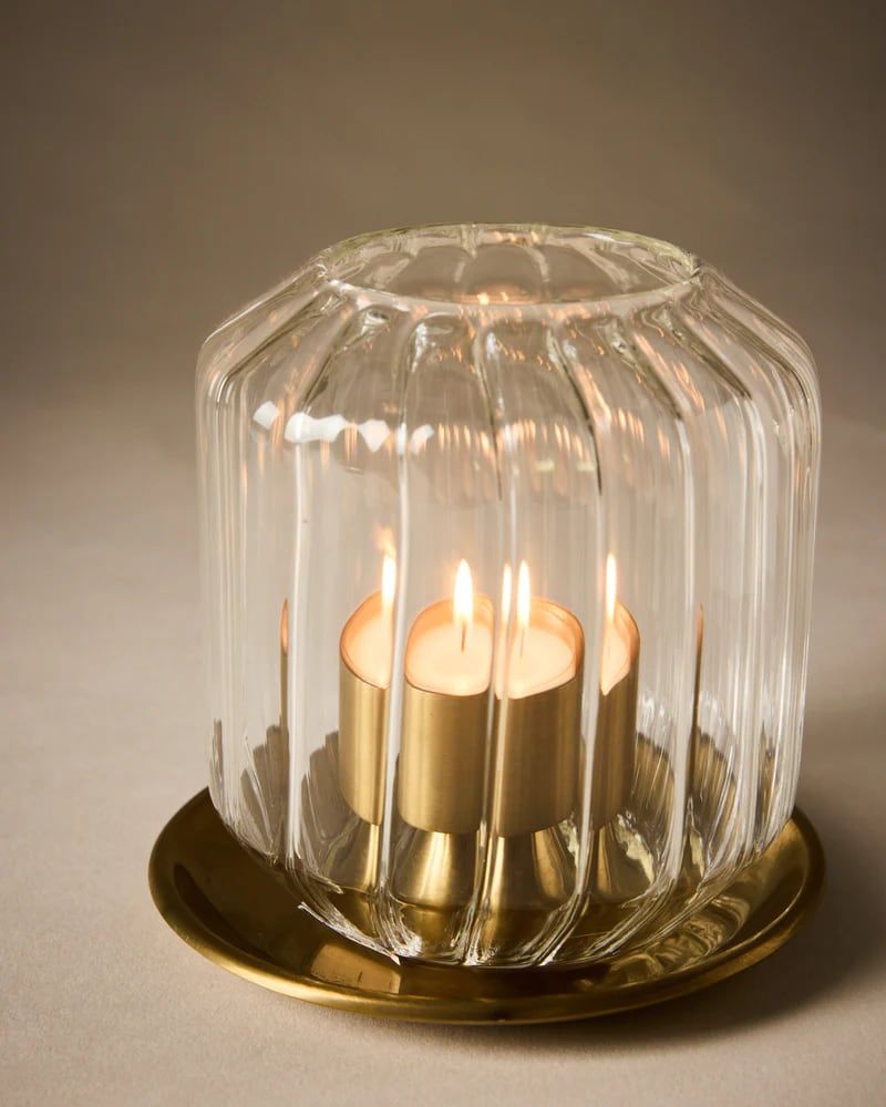 Ribbed glass hurricane lit on a brass base