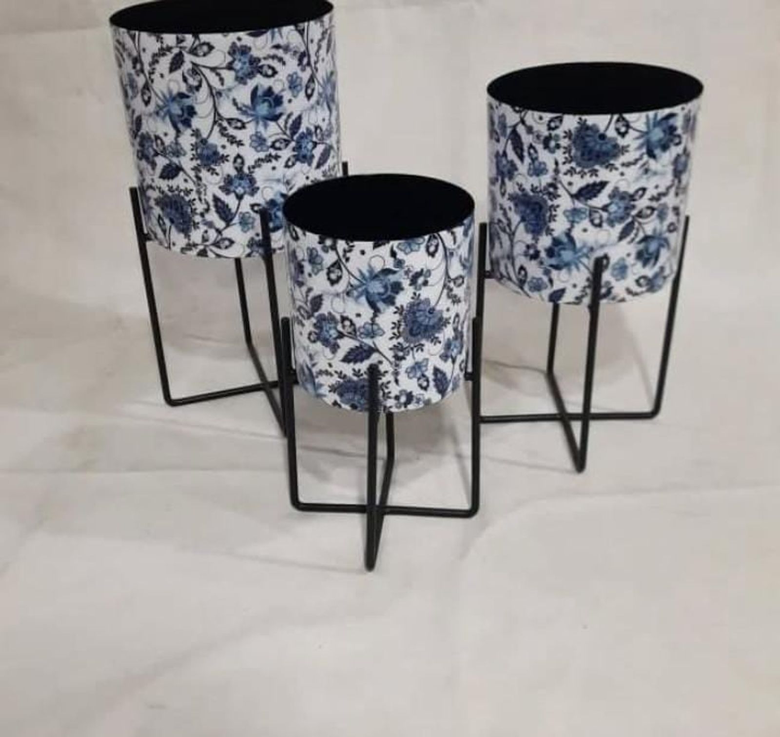 Blue floral-printed metal planters on black stands