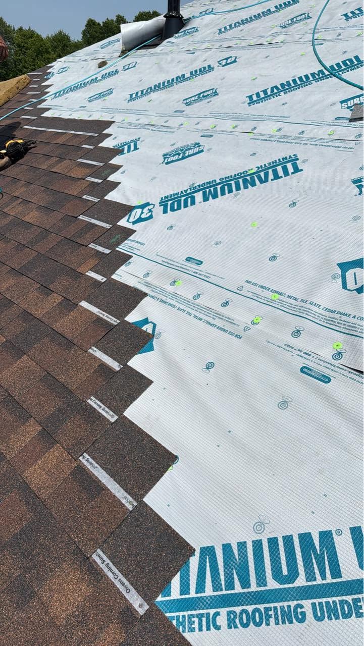 New brown shingles going on at the edge of the synthetic underlayment