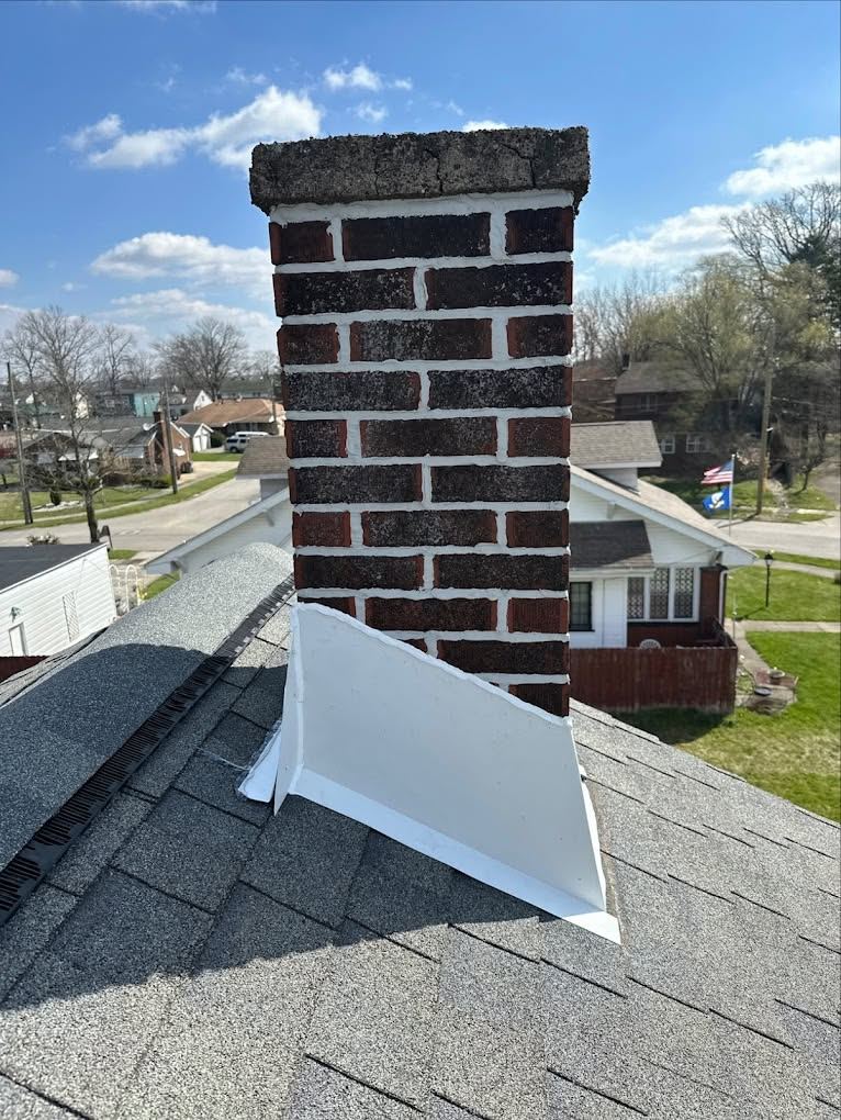 New white metal flashing around the base of a brick chimney