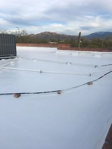 A flat roof with a white coating, a rooftop unit and conduit running across it