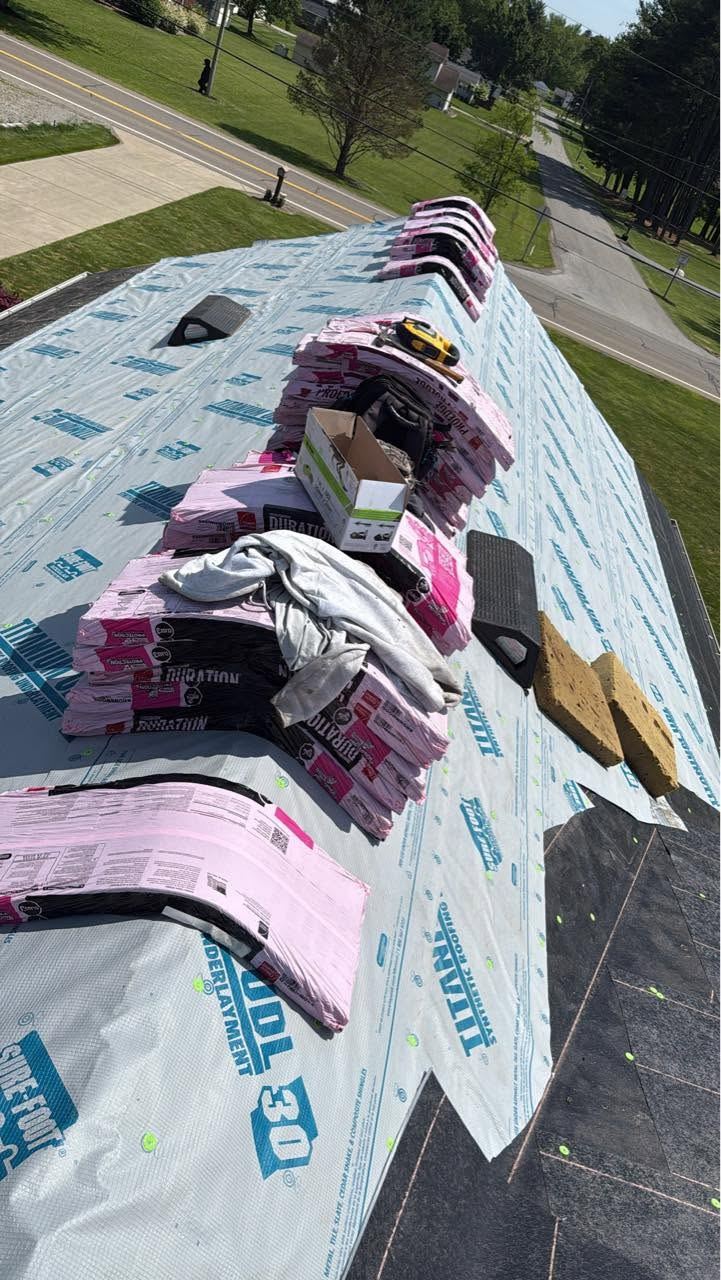 Bundles of shingles laid along the ridge of a roof covered in underlayment